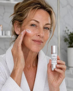 Hyperpigmentation Repair Cream in a silver pump bottle, shown with a woman applying white cream to her cheek