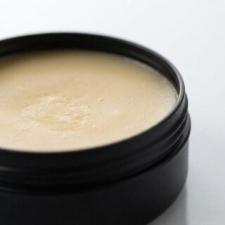 Close-up macro view of the smooth solid cologne balm inside the black jar