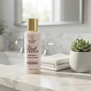 Youth Renew Face Toner bottle displayed on a marble bathroom vanity with white towel and green plant