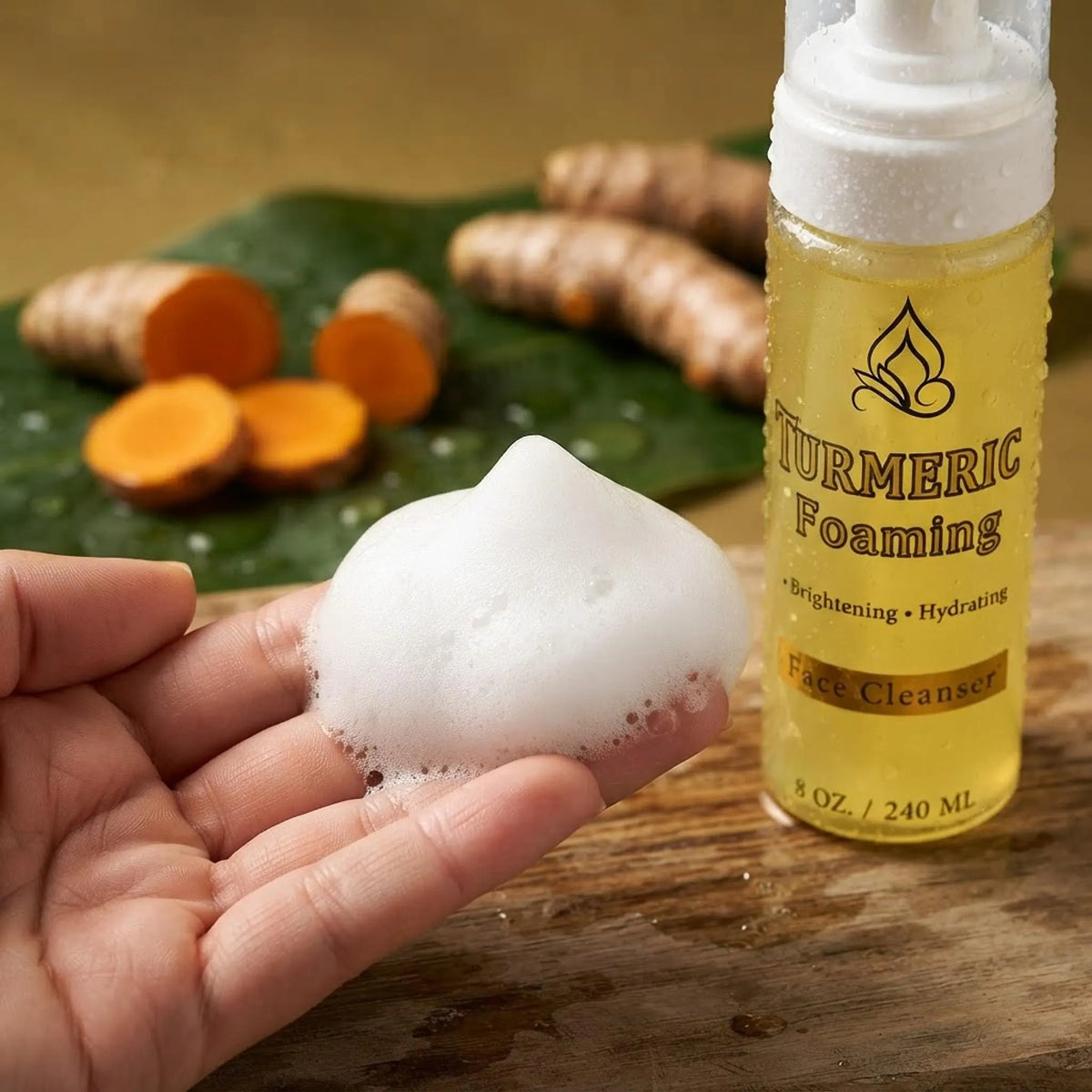 Close-up of rich white foaming face cleanser lather on hands with turmeric root in the background.