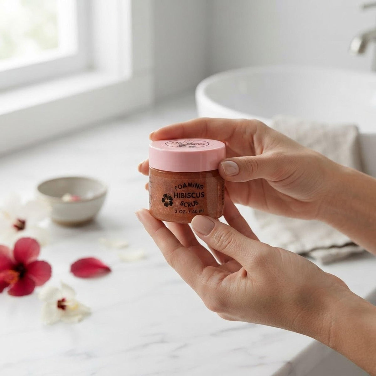 Person holding the 2 oz jar of Natural Foaming Hibiscus Facial Scrub to demonstrate product scale.