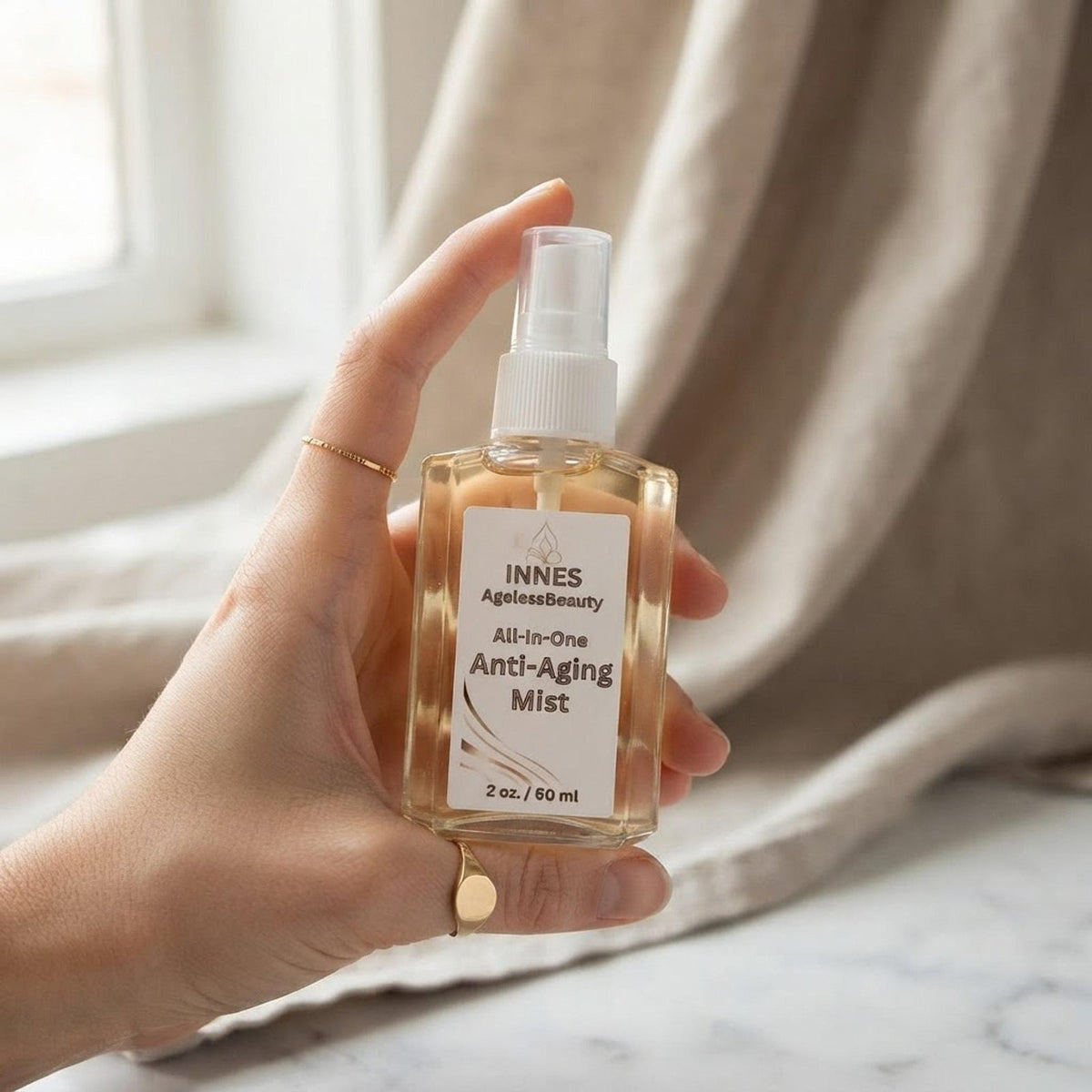 A hand holding the 2 oz Innes Ageless Beauty mist bottle showing its true scale.