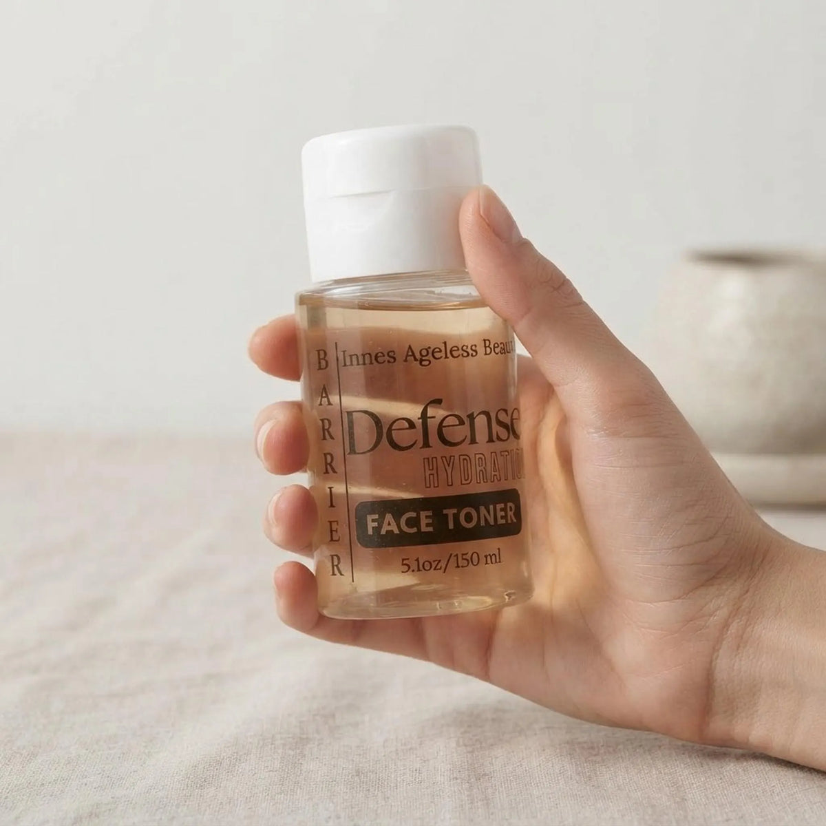 Hand holding the 5.1 oz Barrier Defense Hydrating Toner bottle for scale