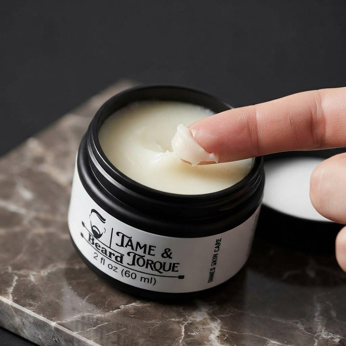 Close-up of fingers scooping the smooth, organic Tame and Torque beard balm from its jar.