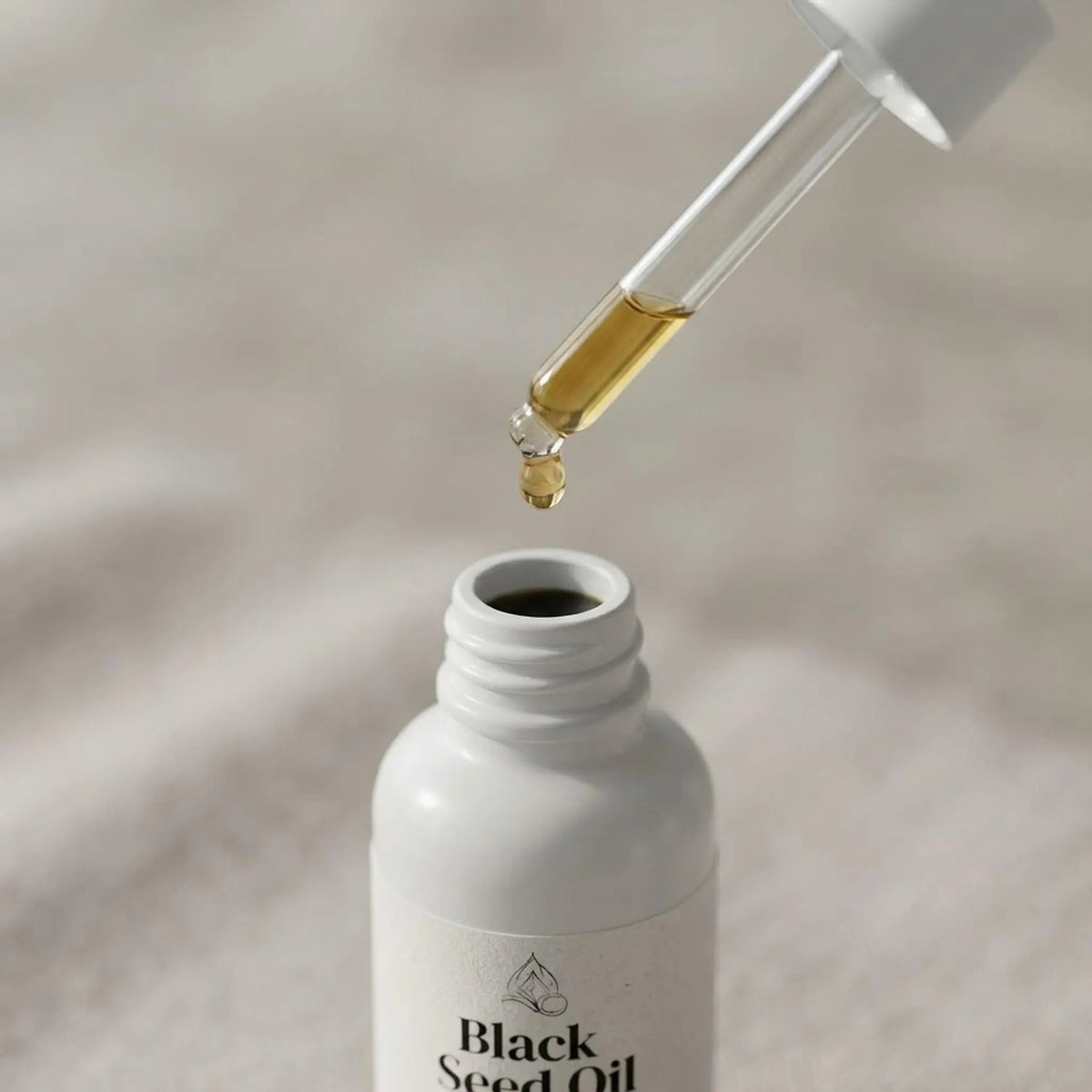 Close-up of golden facial serum dripping from a glass pipette into the bottle.