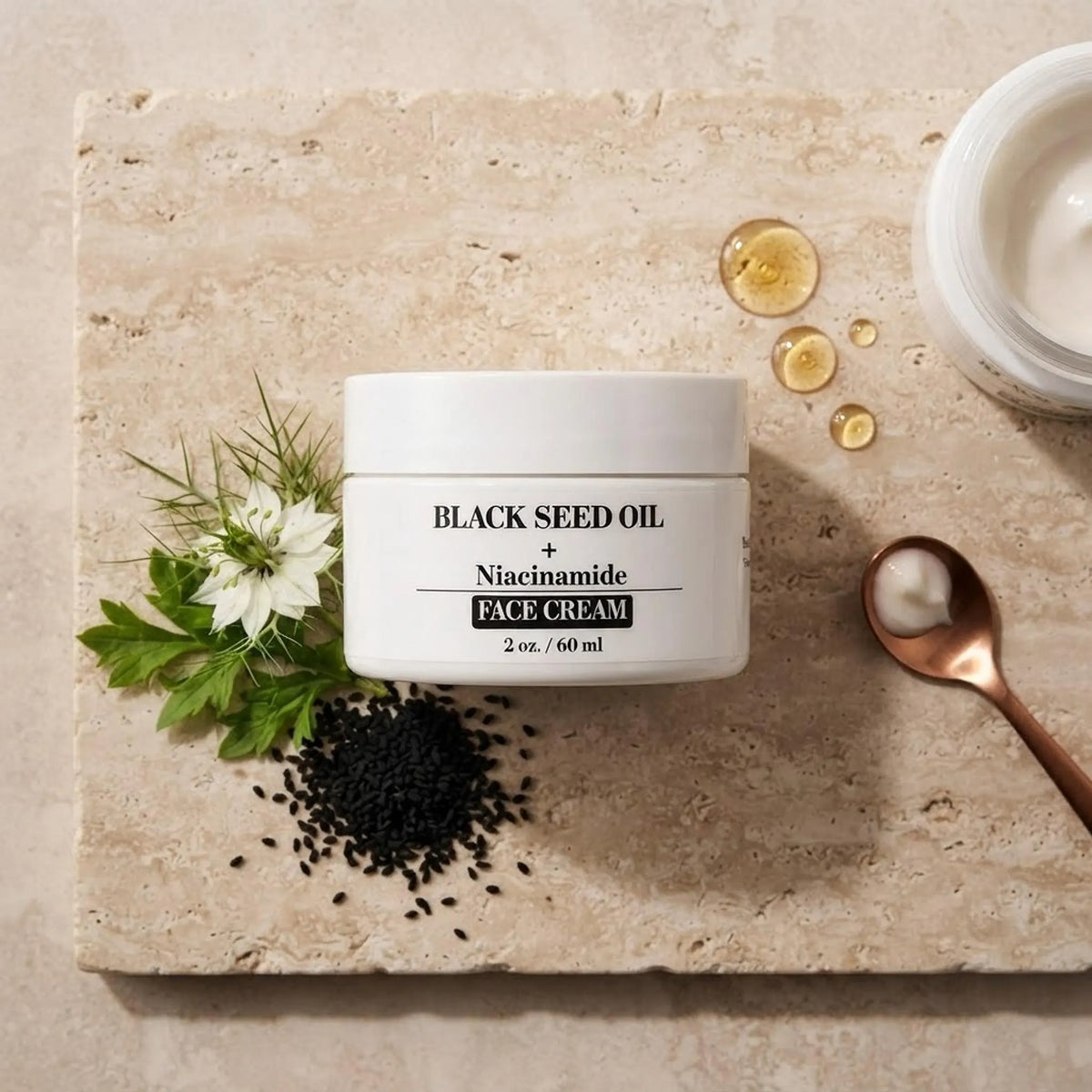 Face cream jar arranged with scattered black seed ingredients and green botanicals on stone.