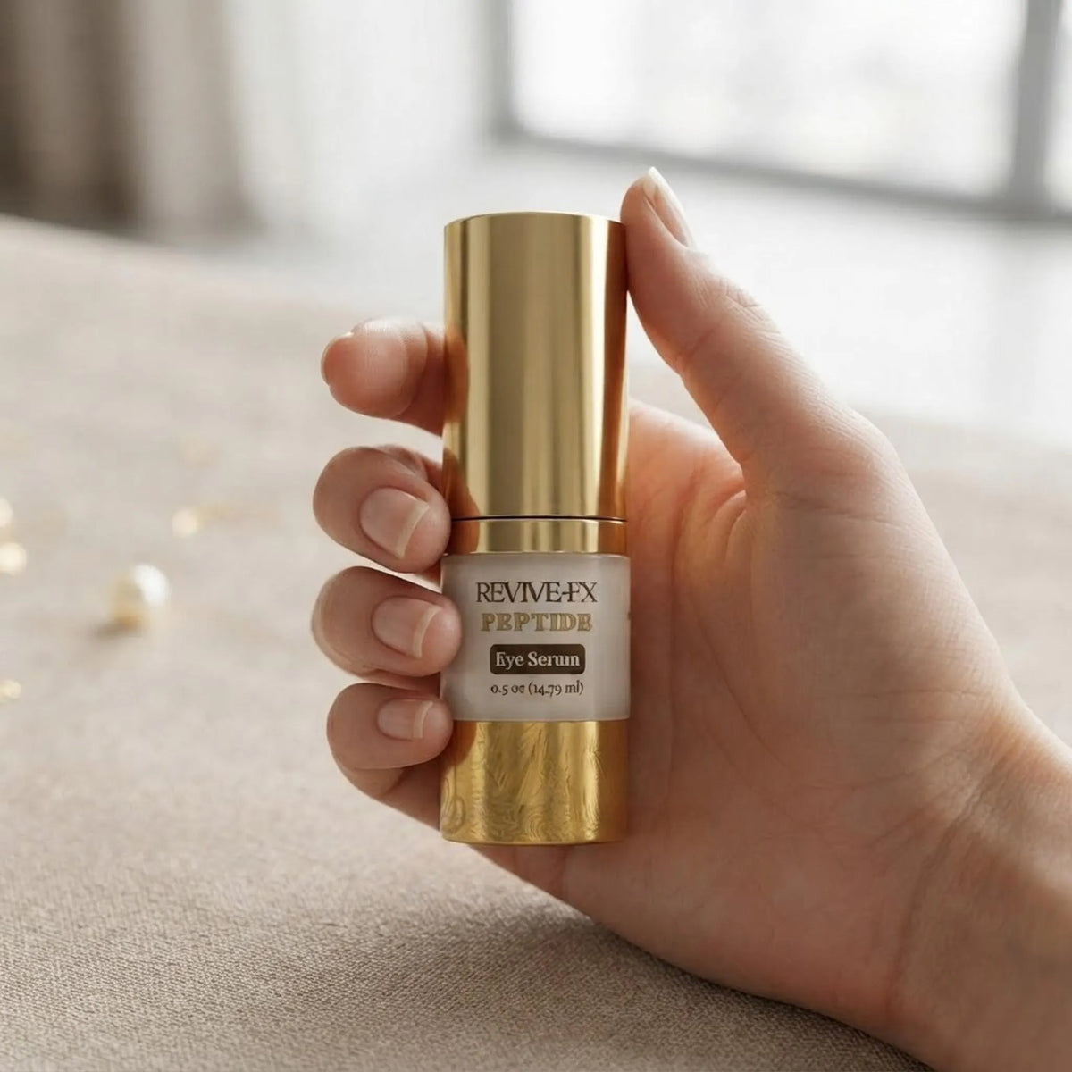 A person holding the 0.5 oz gold pump bottle of ReviveFX Peptide Eye Complex to demonstrate its size