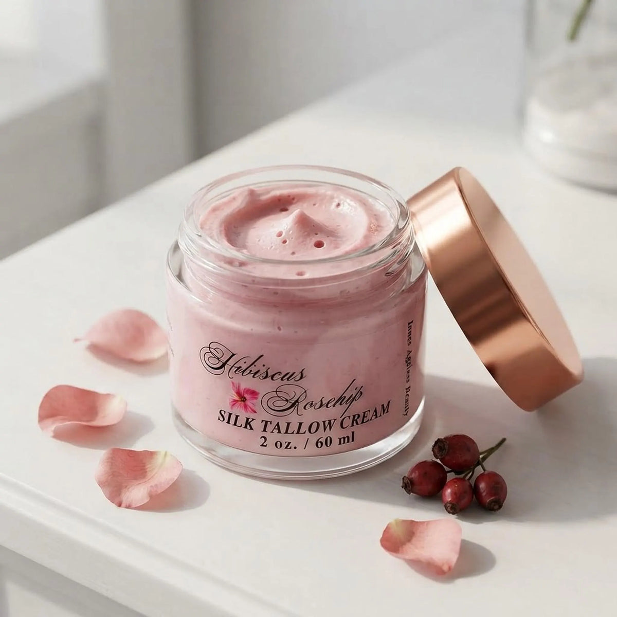 Macro view of open 2 oz jar showing rich pink whipped tallow cream texture with rose gold lid