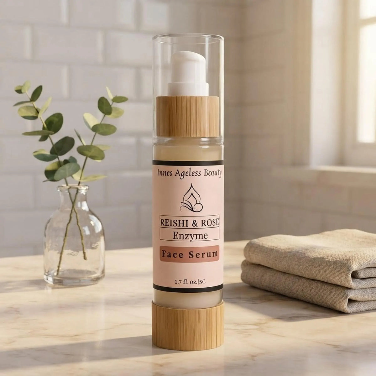 Innes Ageless Beauty Reishi & Rose Enzyme Face Serum bottle on a marble bathroom vanity with eucalyptus and linen towel