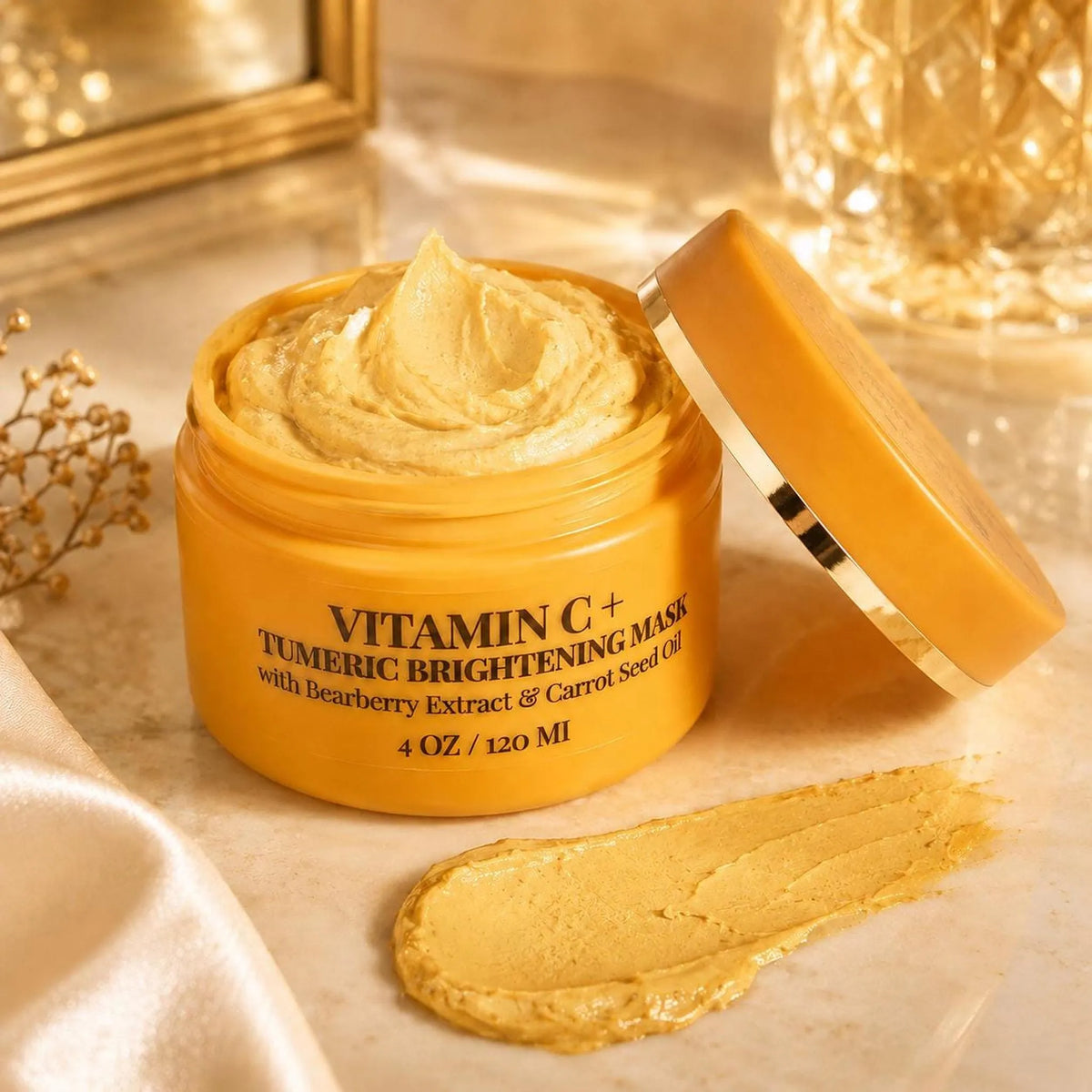 An open yellow jar of Vitamin C+ Turmeric Brightening Mask with a dollop of yellow paste smeared on the marble surface next to it.