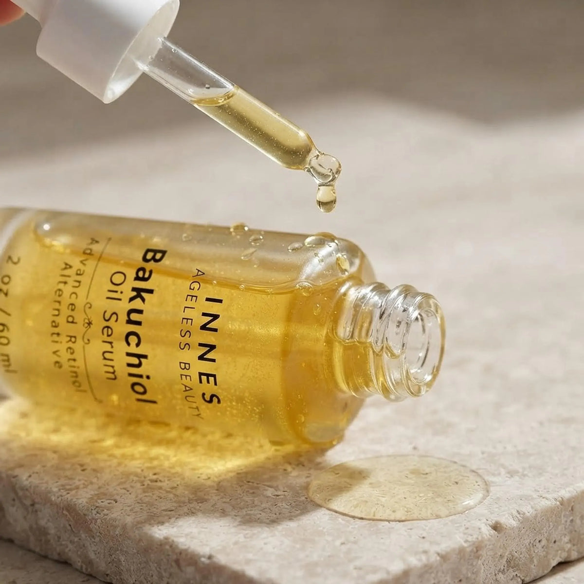 Close-up detail shot of the Bakuchiol Oil Serum bottle with a golden droplet falling from the dropper.