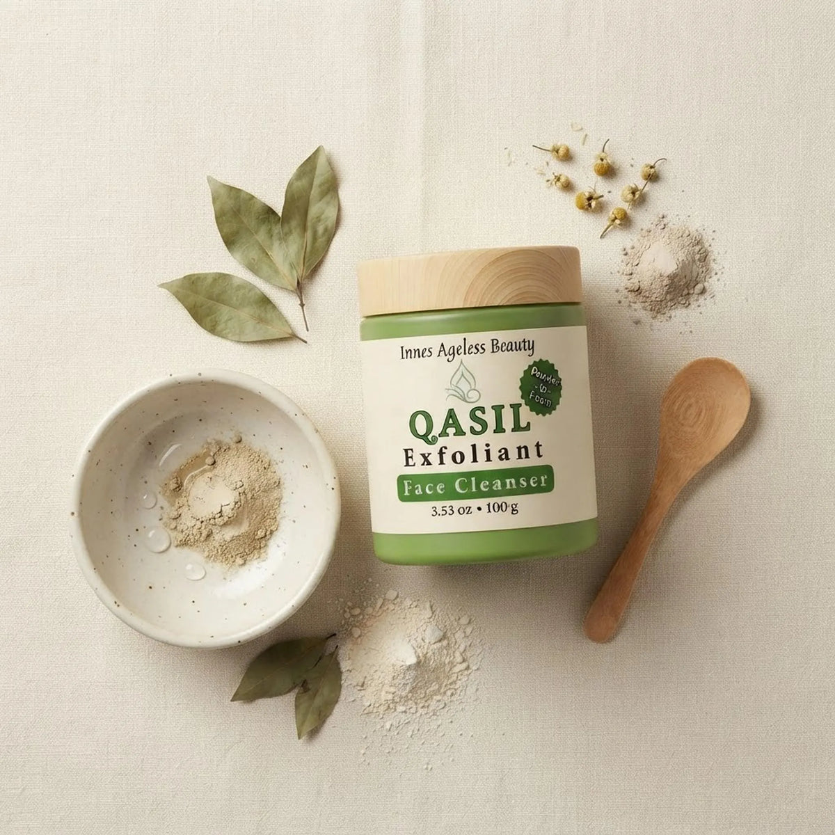 Flat lay showing the Qasil Exfoliant Face Cleanser jar, wooden spoon, and ceramic bowl on a neutral surface