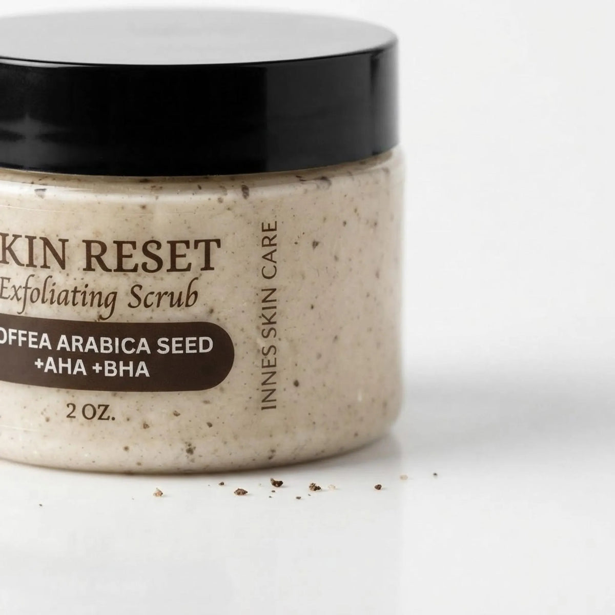 Coffee exfoliating face scrub jar on a marble bathroom counter with towel and greenery