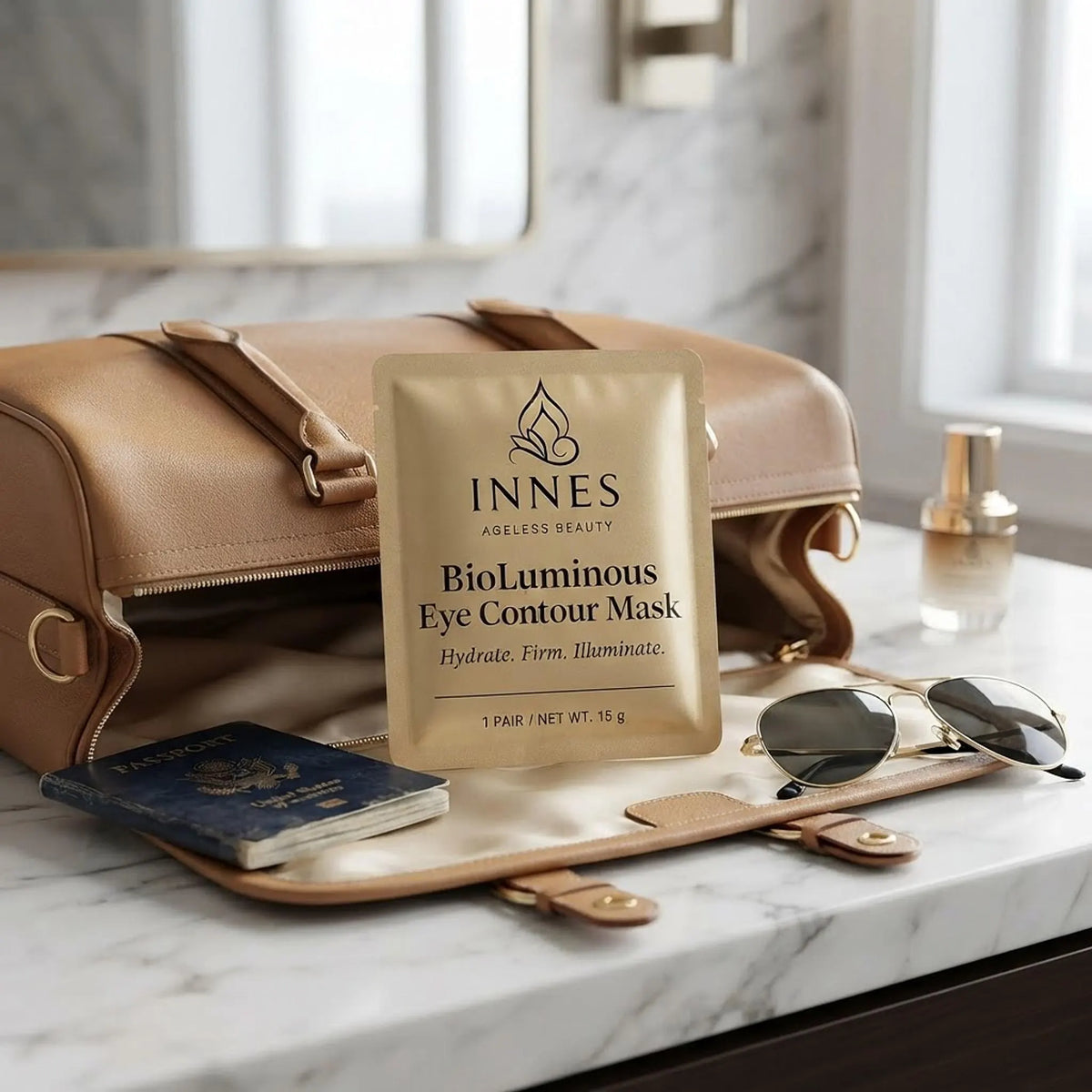 Overhead flat lay of the gold Innes BioLuminous Eye Contour Mask pouch on beige linen with chamomile flowers and serum.