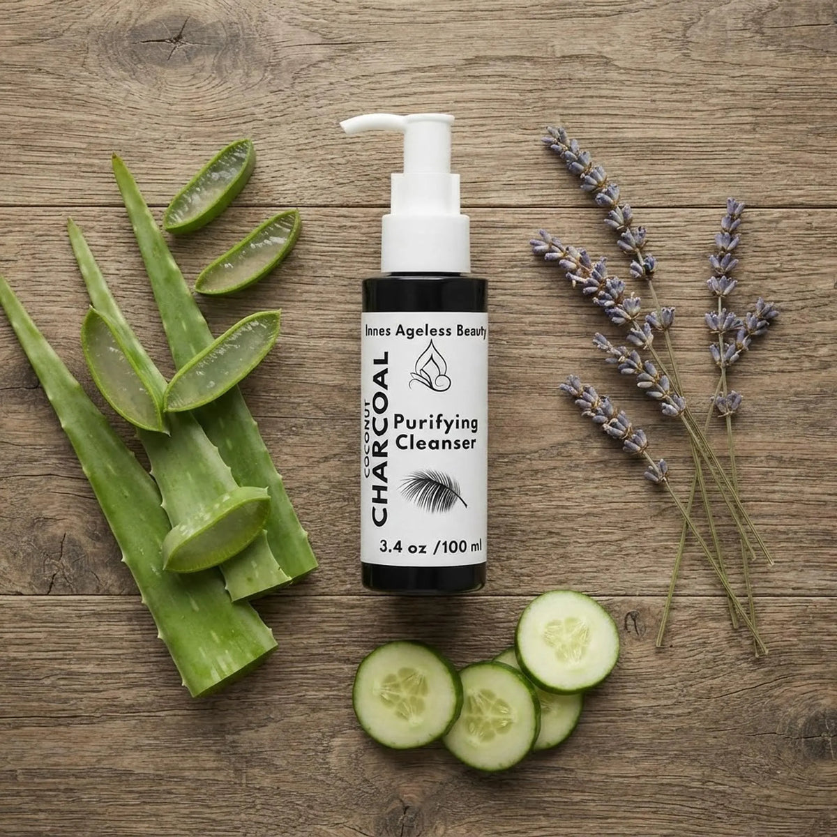 Flat lay of charcoal cleanser bottle surrounded by fresh aloe vera, lavender, and cucumber slices.