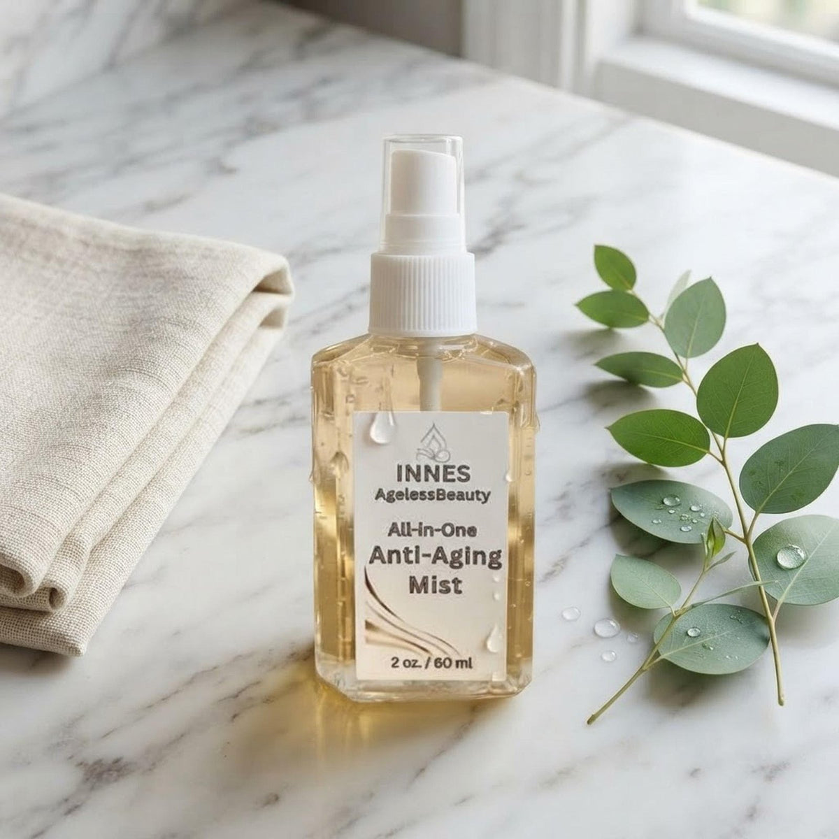 Skincare flatlay featuring the Innes Ageless Beauty mist bottle with a linen towel and botanical sprig.