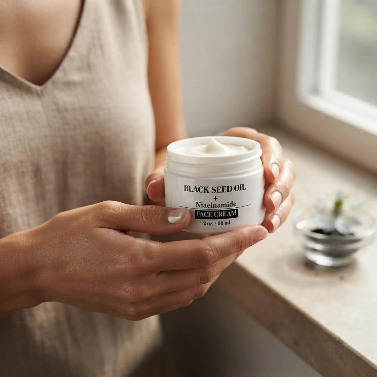 A person holding the face cream jar to demonstrate its actual size in hand.