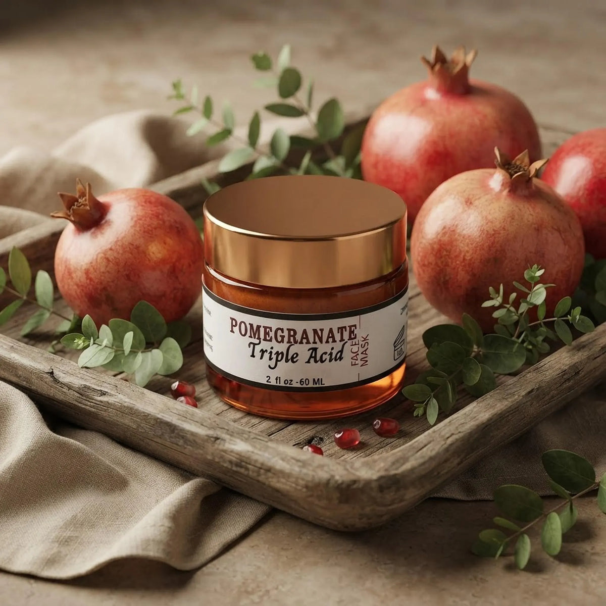 Pomegranate face mask jar styled on a wooden tray with fresh pomegranates and green leaves