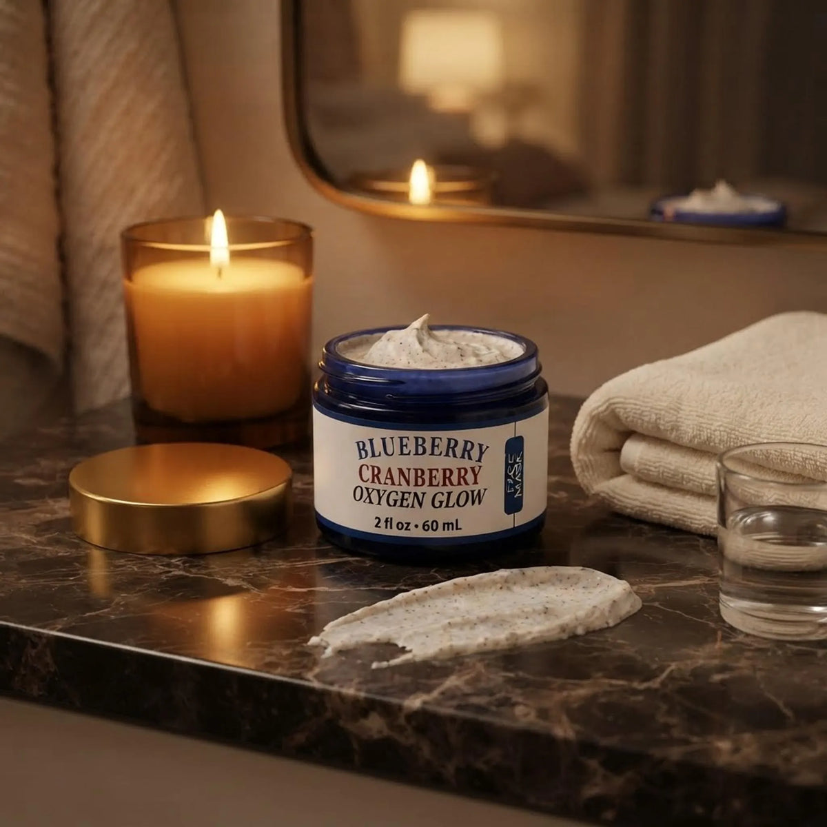 The face mask jar displayed on a marble vanity next to a candle and a hand towel for a nighttime routine.